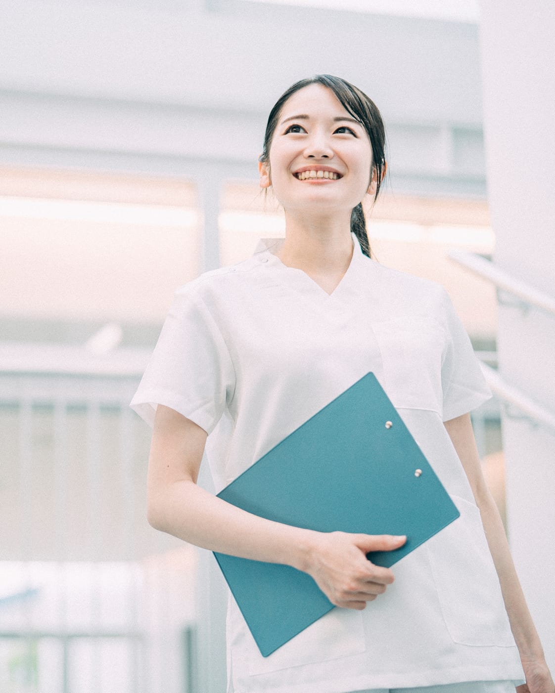 院内の明るい廊下で笑顔を見せる看護師